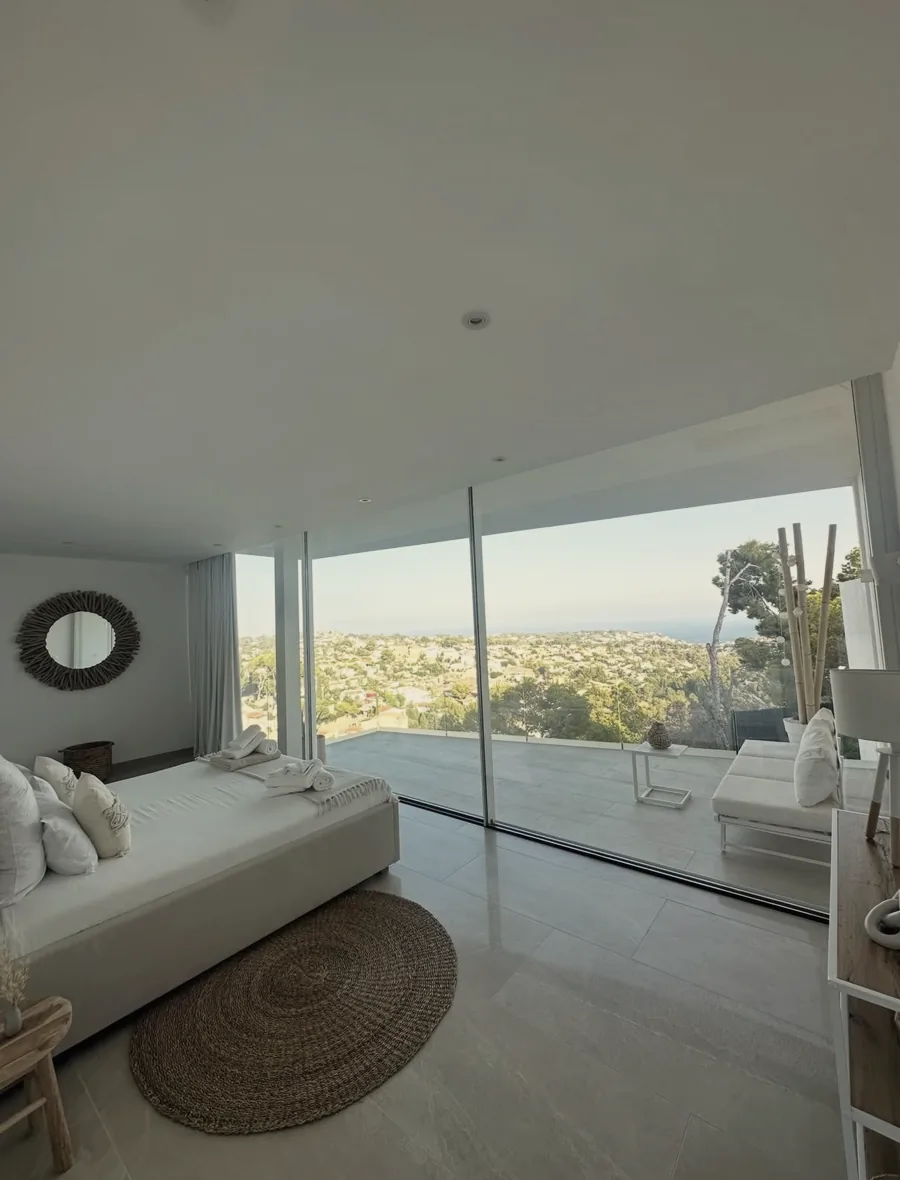 Schlafzimmer mit raumhohen Fenstern und Blick über die Küste